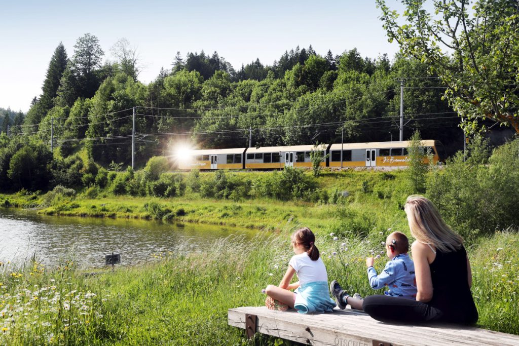 Familie sitzt am See, Mariazellerbahn fährt vorbei