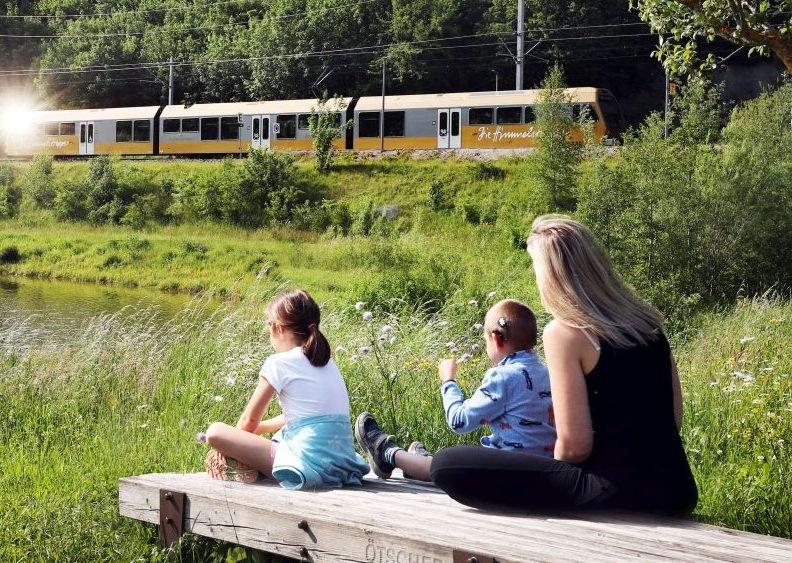 Familie sitzt am See, Mariazellerbahn fährt vorbei